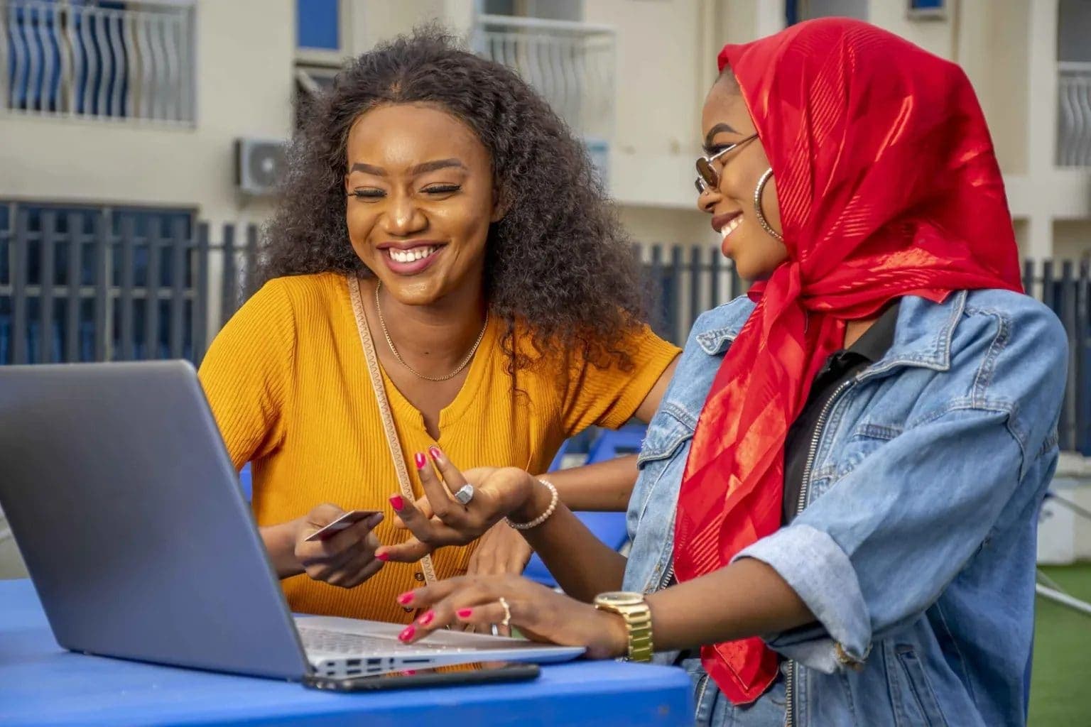 Two women smiling as they work together on a laptop