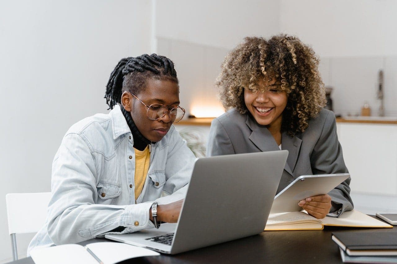 Two colleagues reviewing work together on a laptop